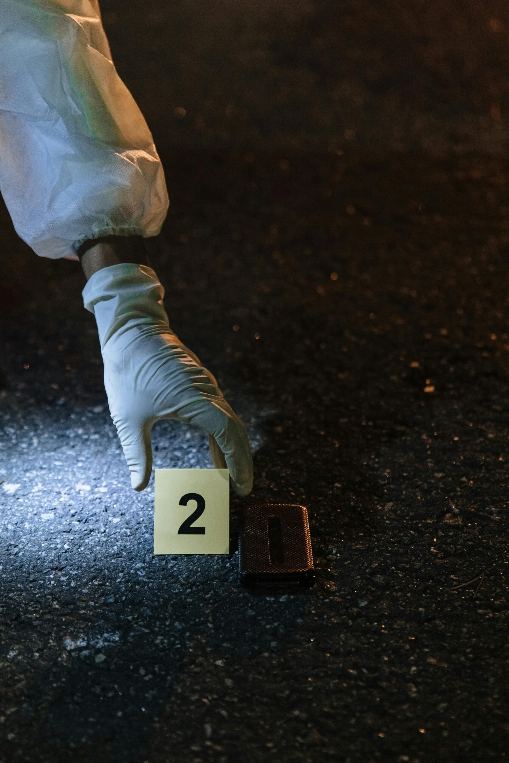 A forensic investigator examines evidence at a night crime scene on city streets.