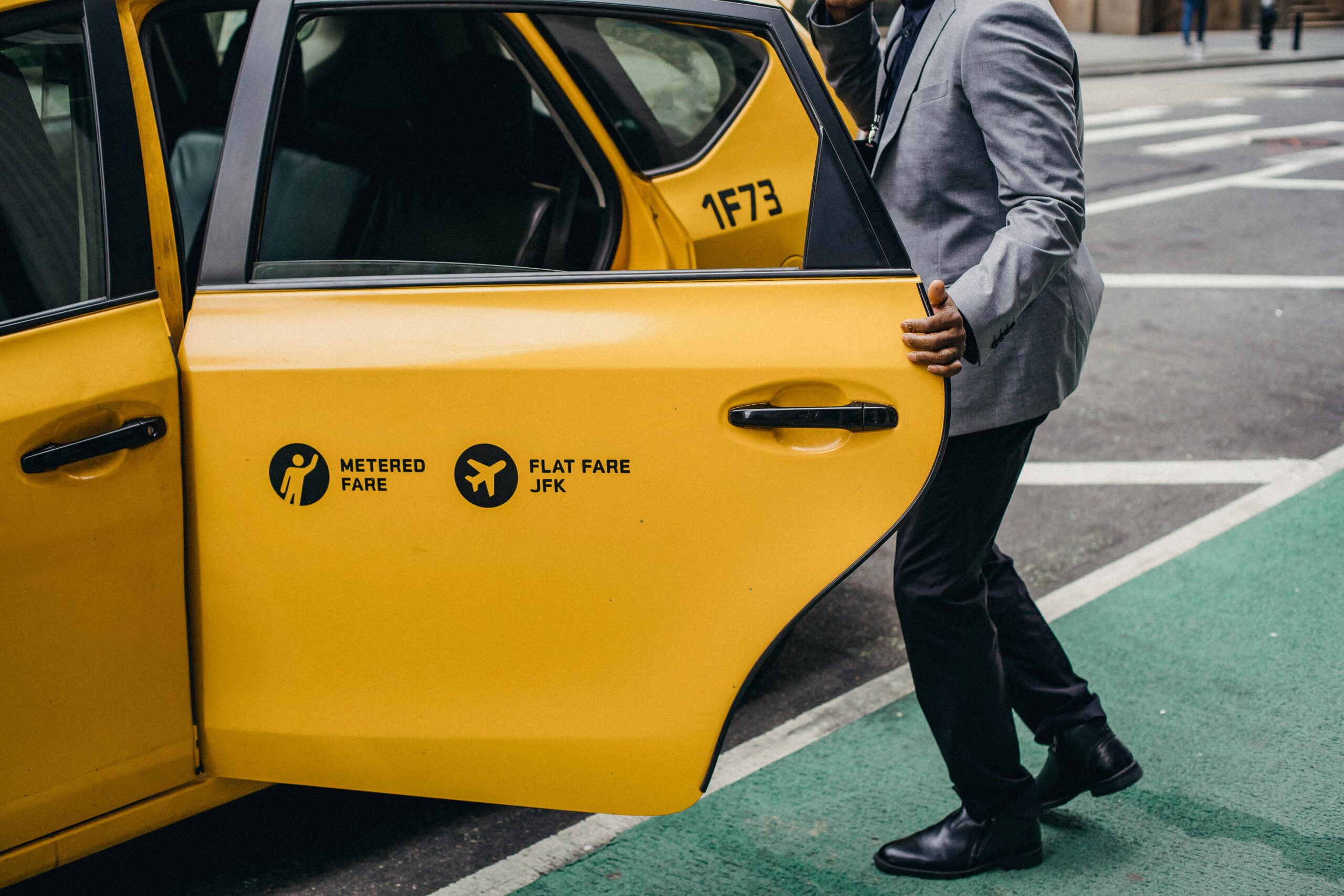 Side view crop anonymous African American male in formal suit opening taxi door parked on street