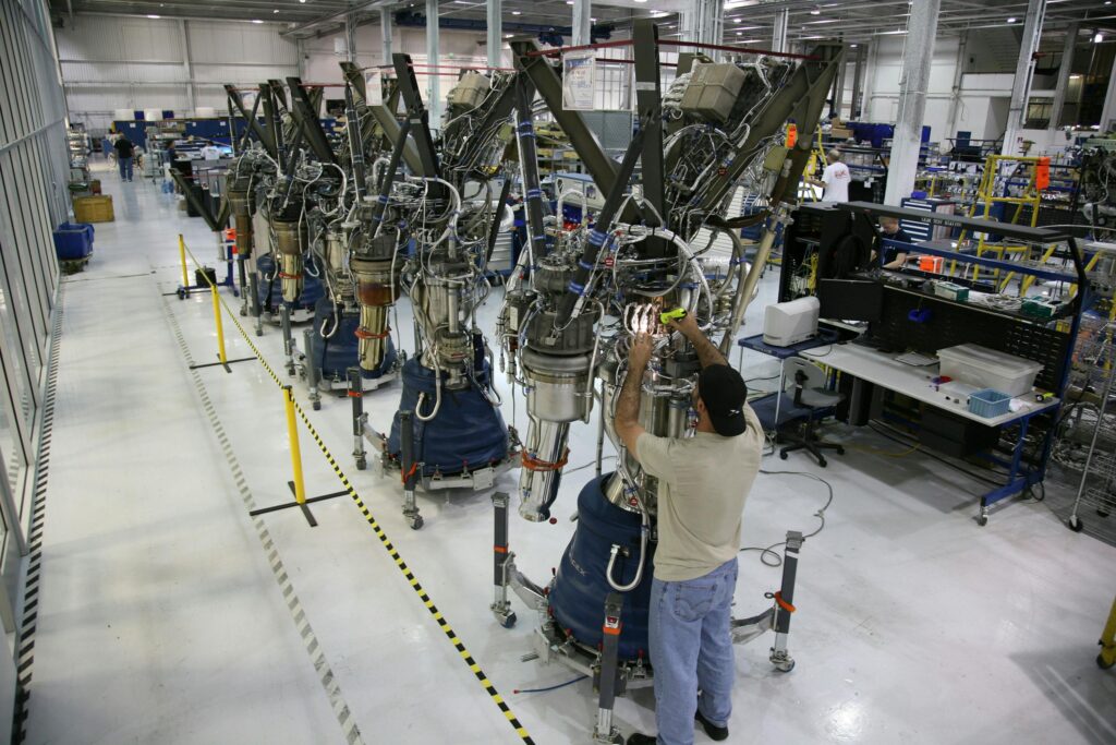 From above back view of unrecognizable male technician checking details of new spaceship at modern rocket factory